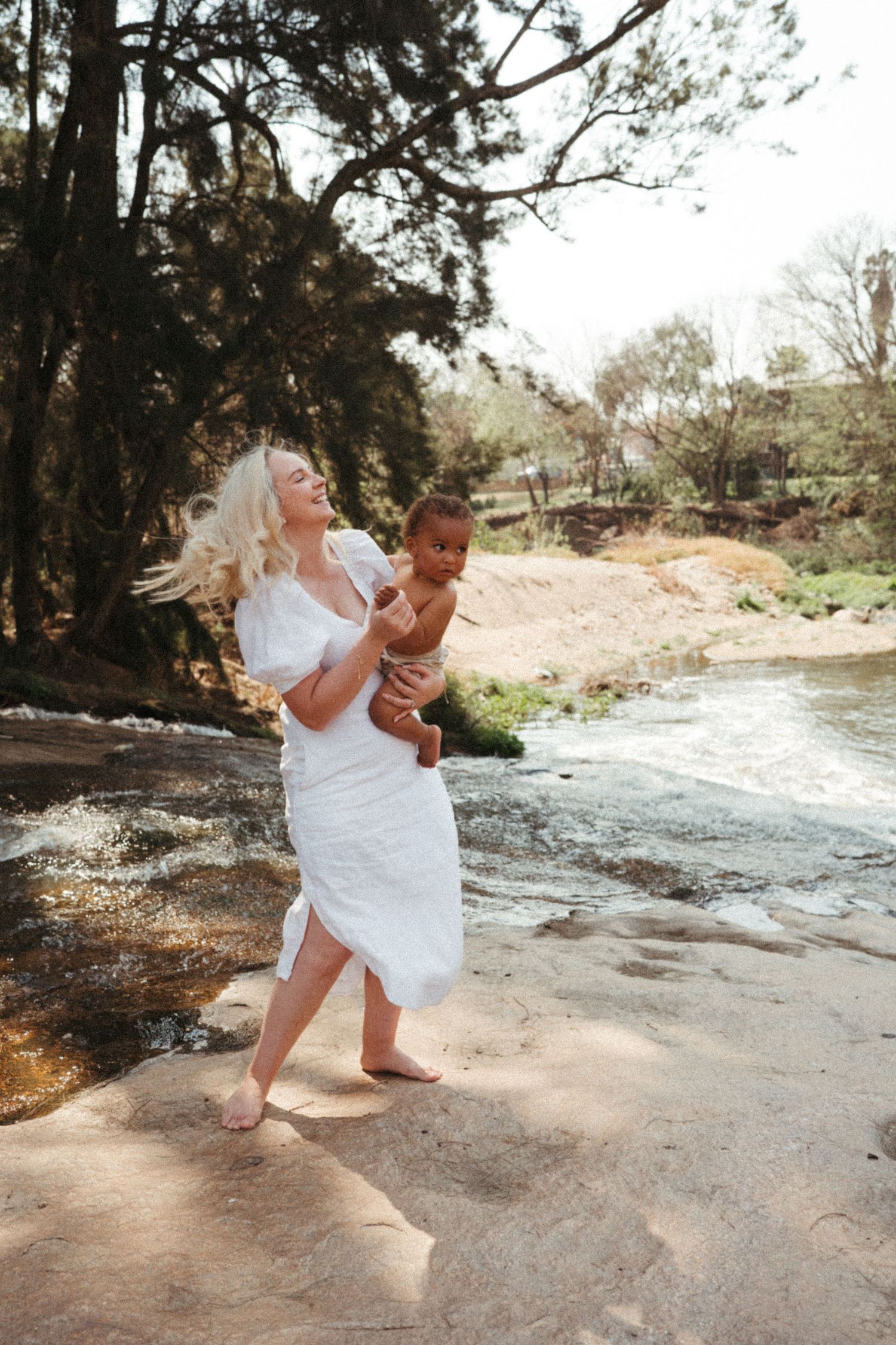 Intimate black and white photographs showing loving interaction between adult and child on rocky ground.