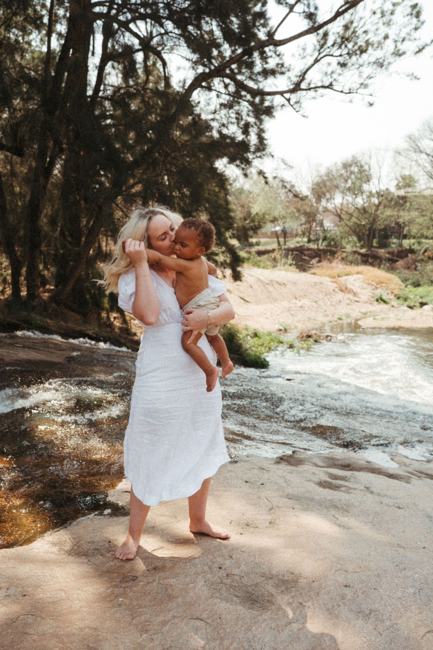Natural outdoor portrait series capturing precious moments between caregiver and child by water.