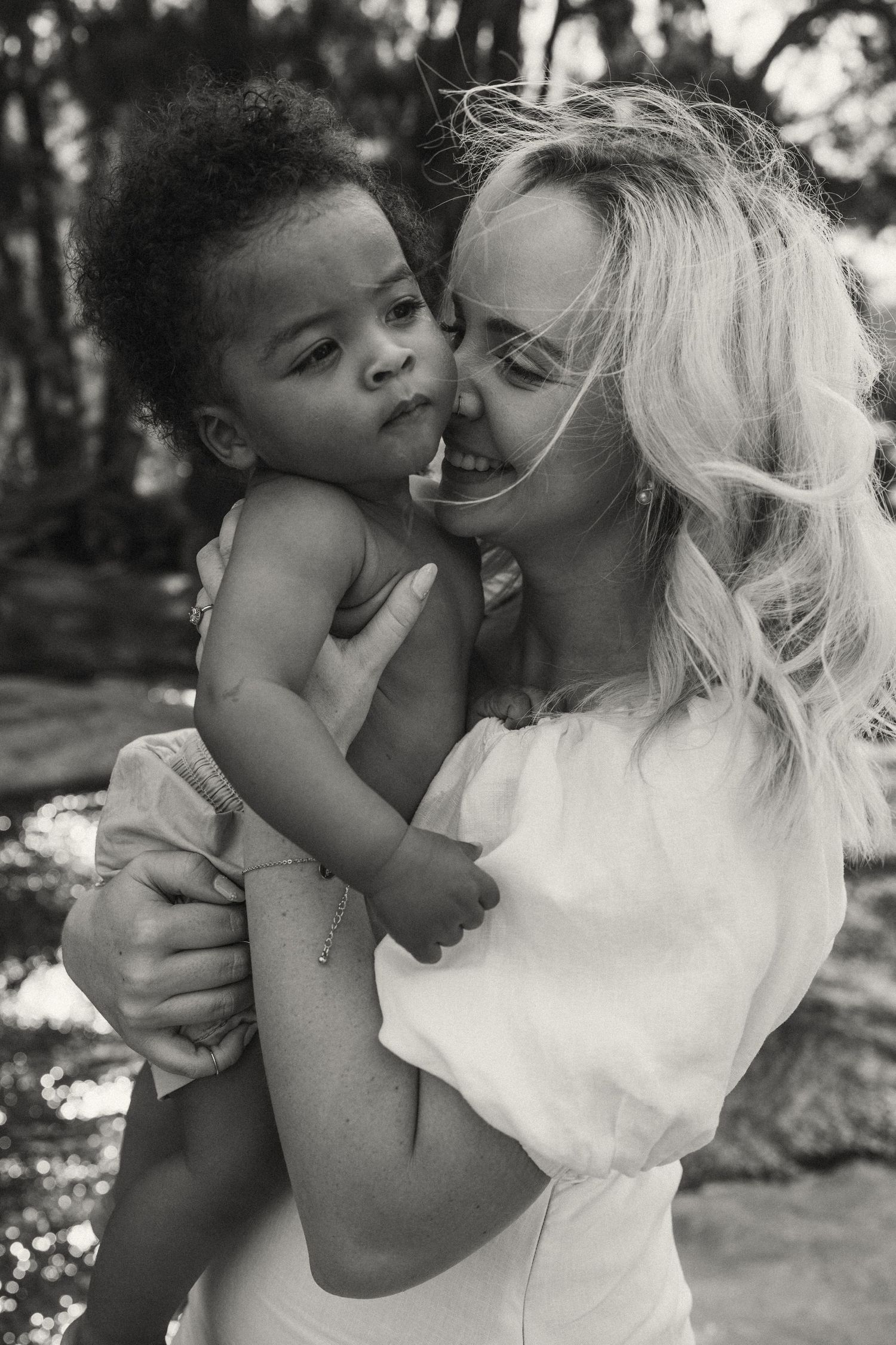 Black and white portrait capturing intimate moments of affection between parent and child.