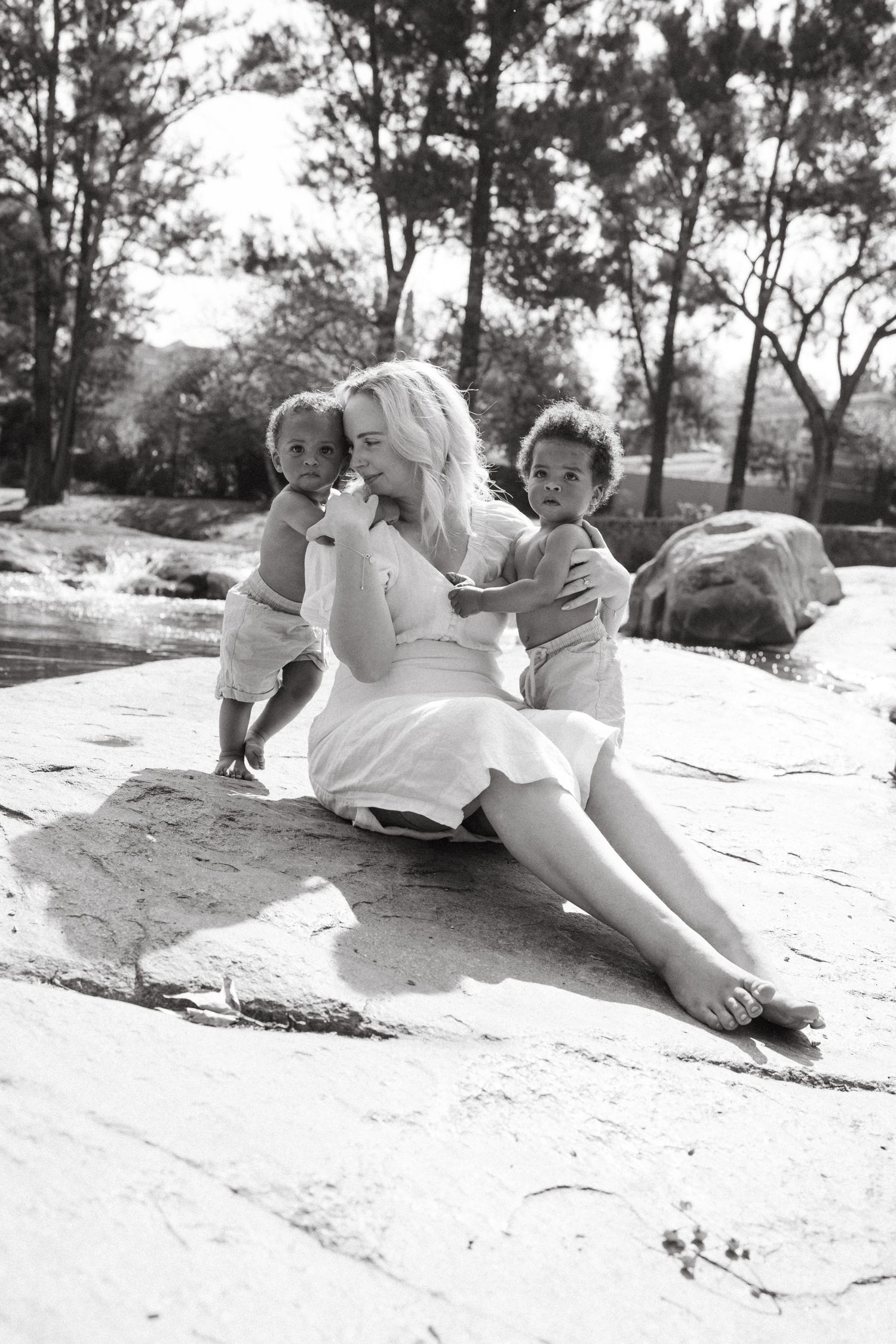 A sweet moment captured in black and white on a rocky surface outdoors.