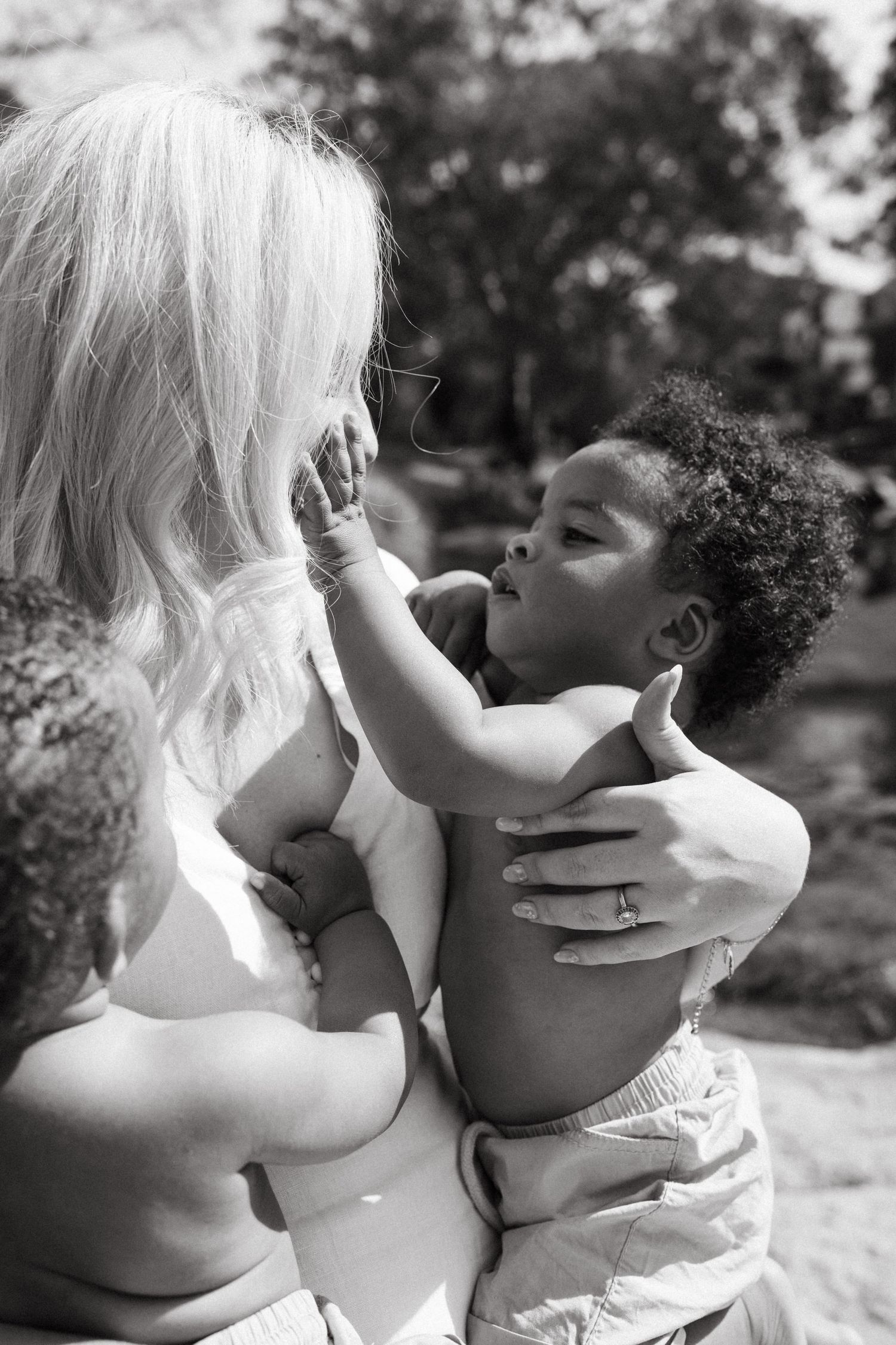 Black and white photo showing gentle interactions in natural lighting between a mother and her twins in Johannesburg