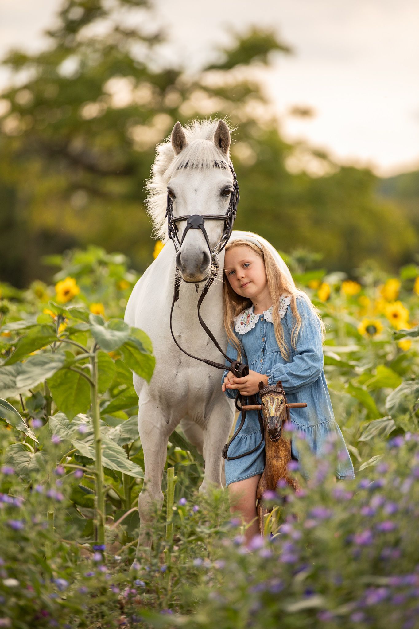 A large cream-colored draft horse and its companion pause together in a sunlit autumn forest.