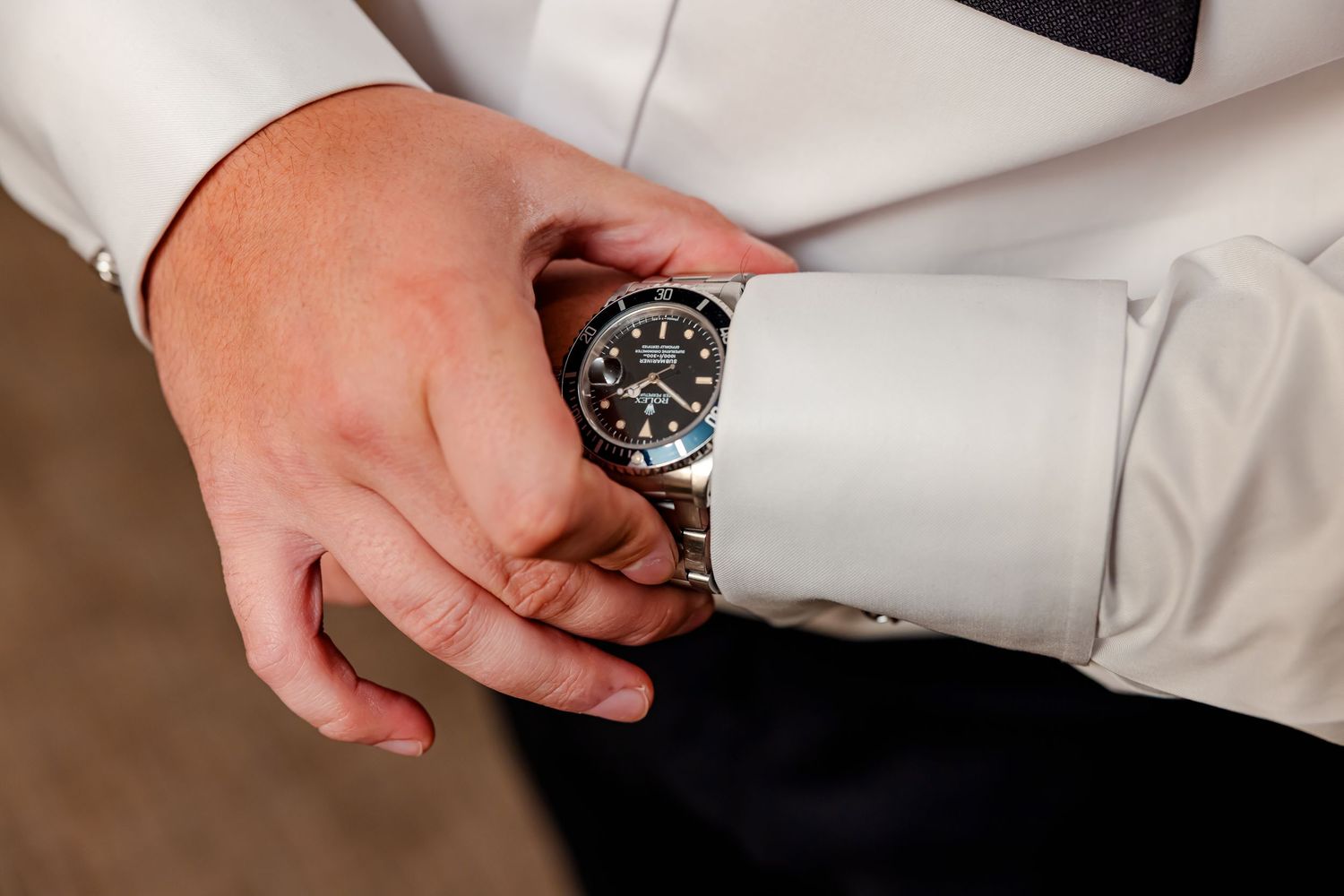 A hand wearing a black wristwatch and white dress shirt sleeve shown from multiple angles.