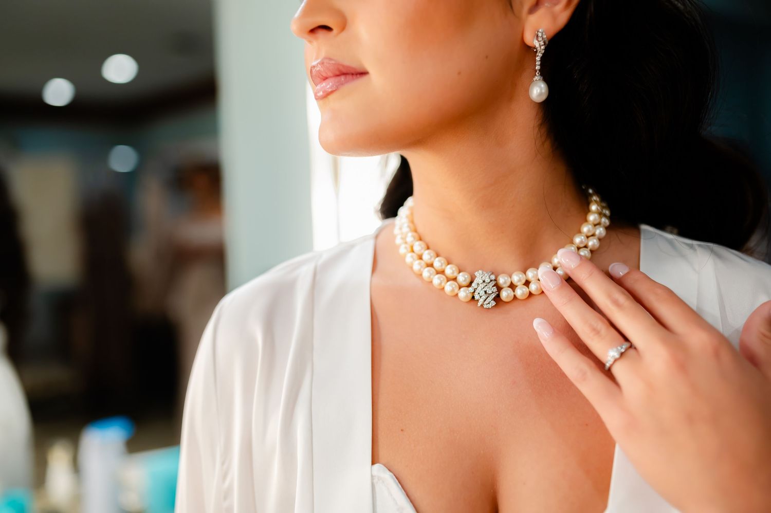 Close-up view of an elegant pearl necklace and earrings set worn with a white top.