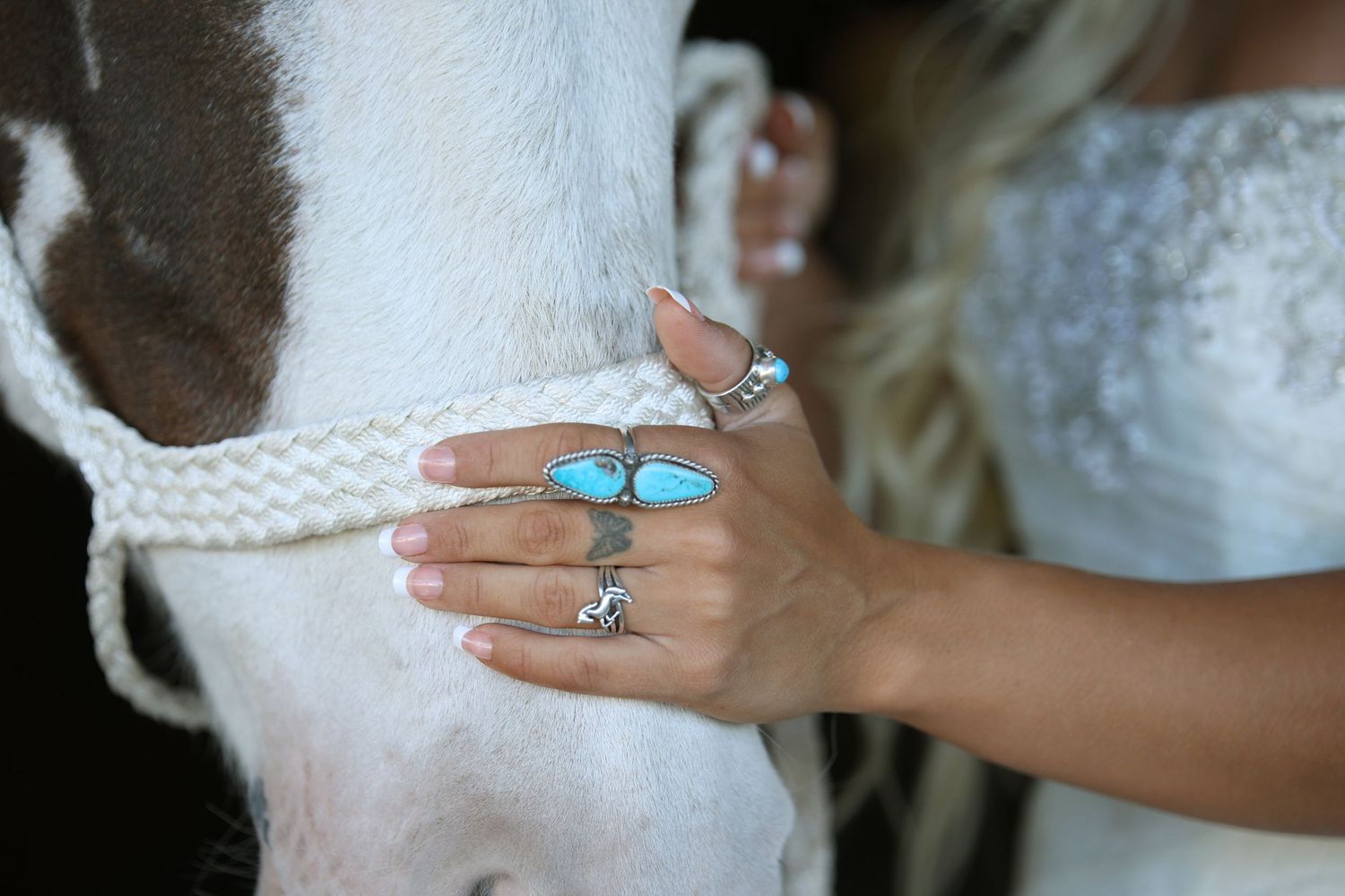 close up of bride's hand on horse's nose wearing turquoise jewelry
