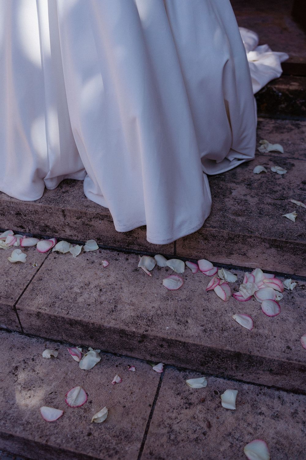 la robe de la mariée à la sortie de l'église avec des pétales de roses