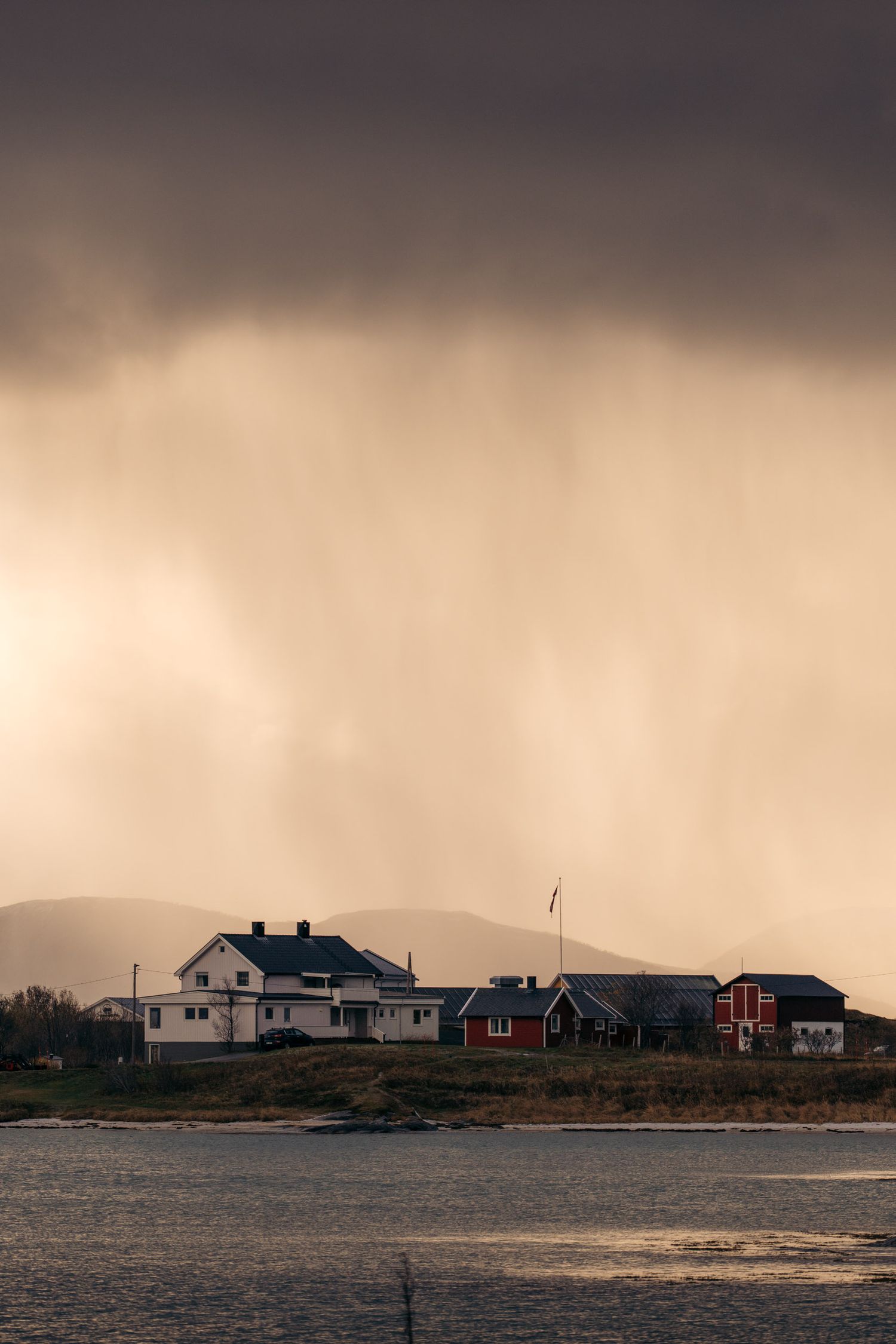 pluie et soleil au-dessus de maisons norvégiennes de sommaroy au bord du fjord