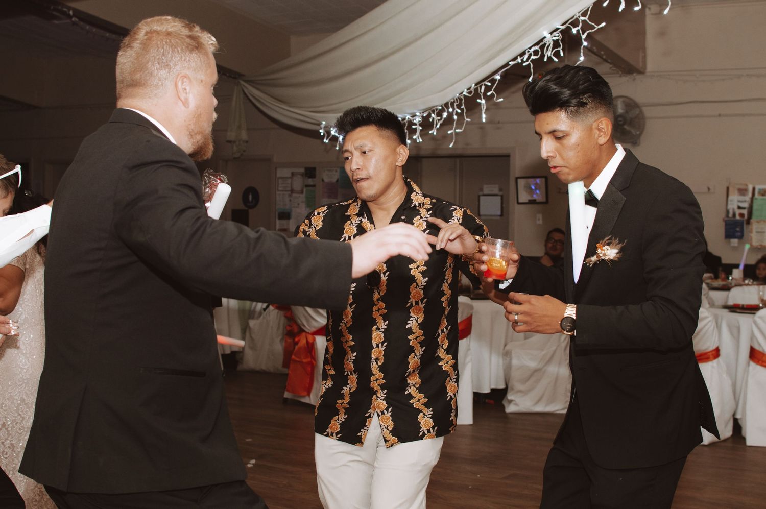 Wedding reception dance floor filled with guests celebrating in formal attire.