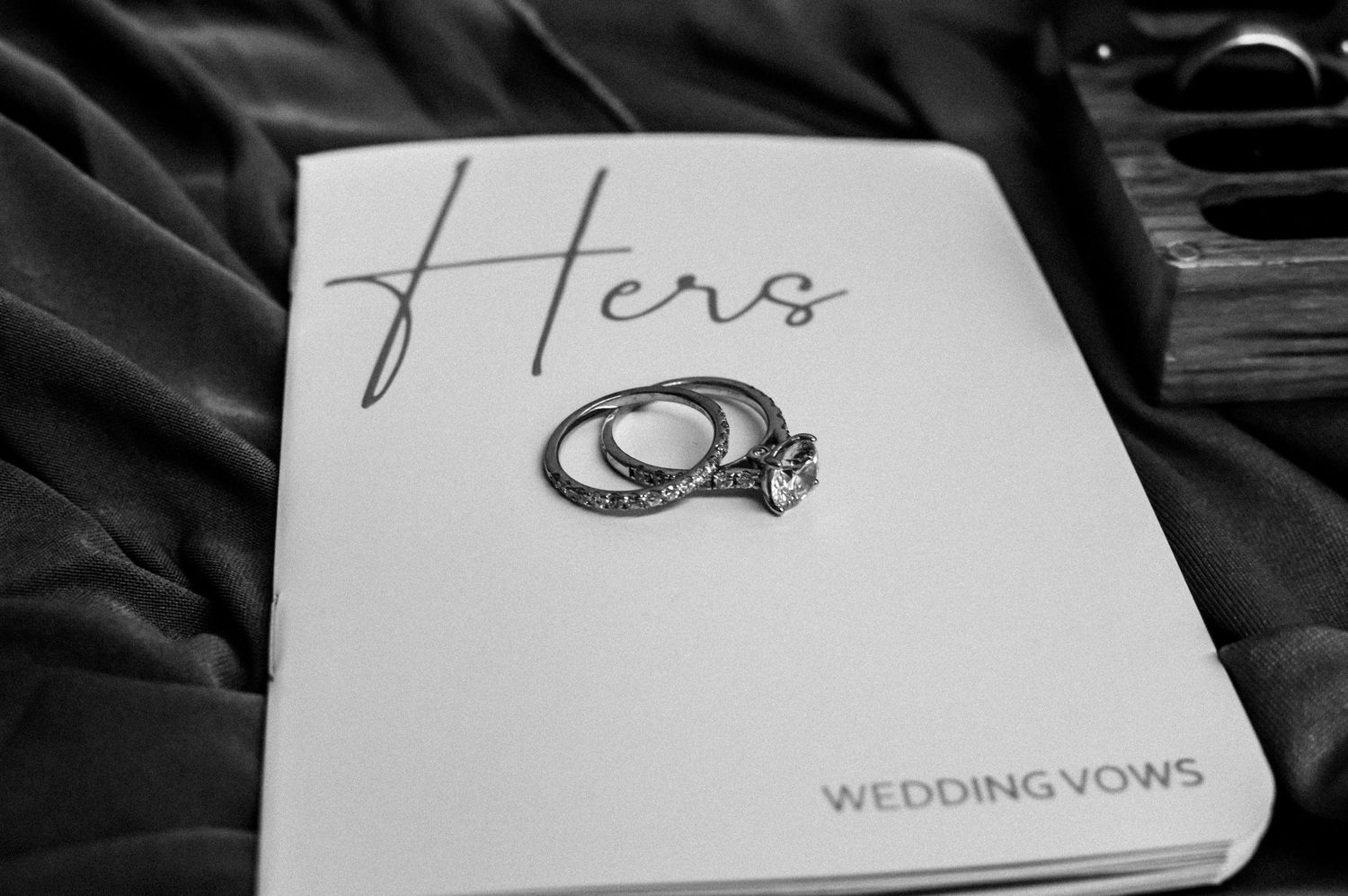 Wedding vows and rings paperwork laid out on dark background.
