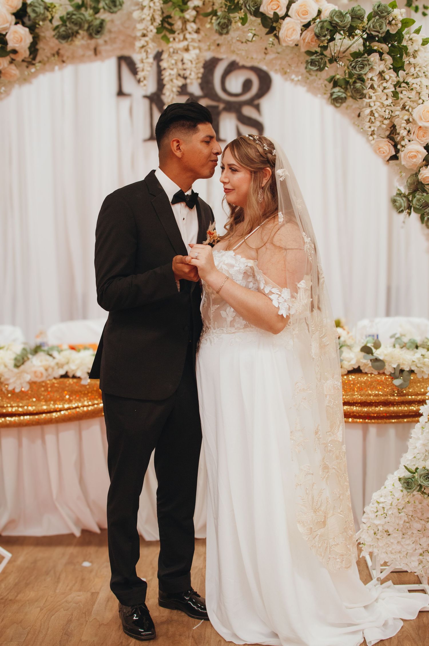 Newlyweds share a romantic dance moment under floral decorations at their wedding reception.