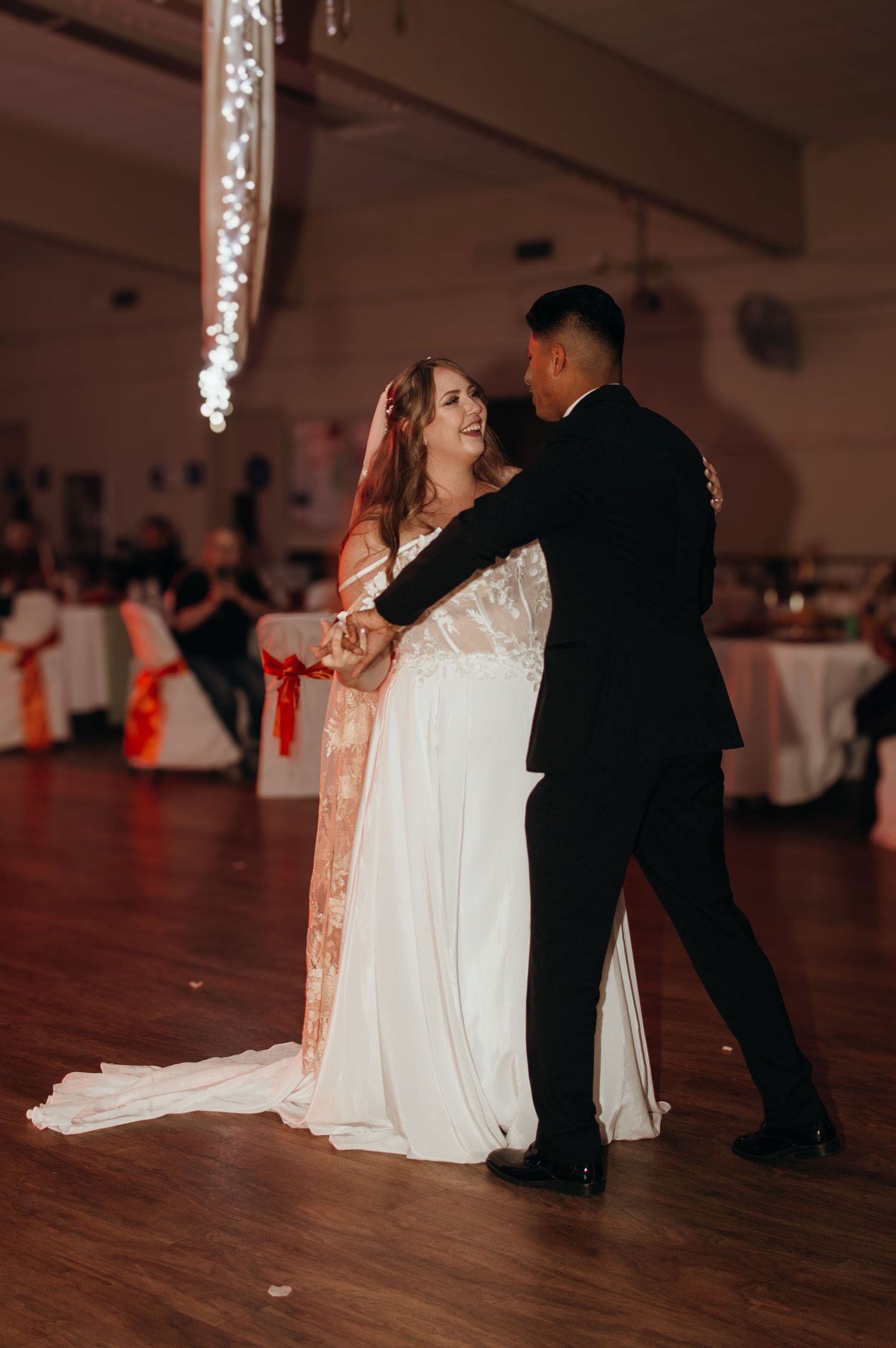 Wedding couple dancing in a dimly lit reception hall with romantic lighting.