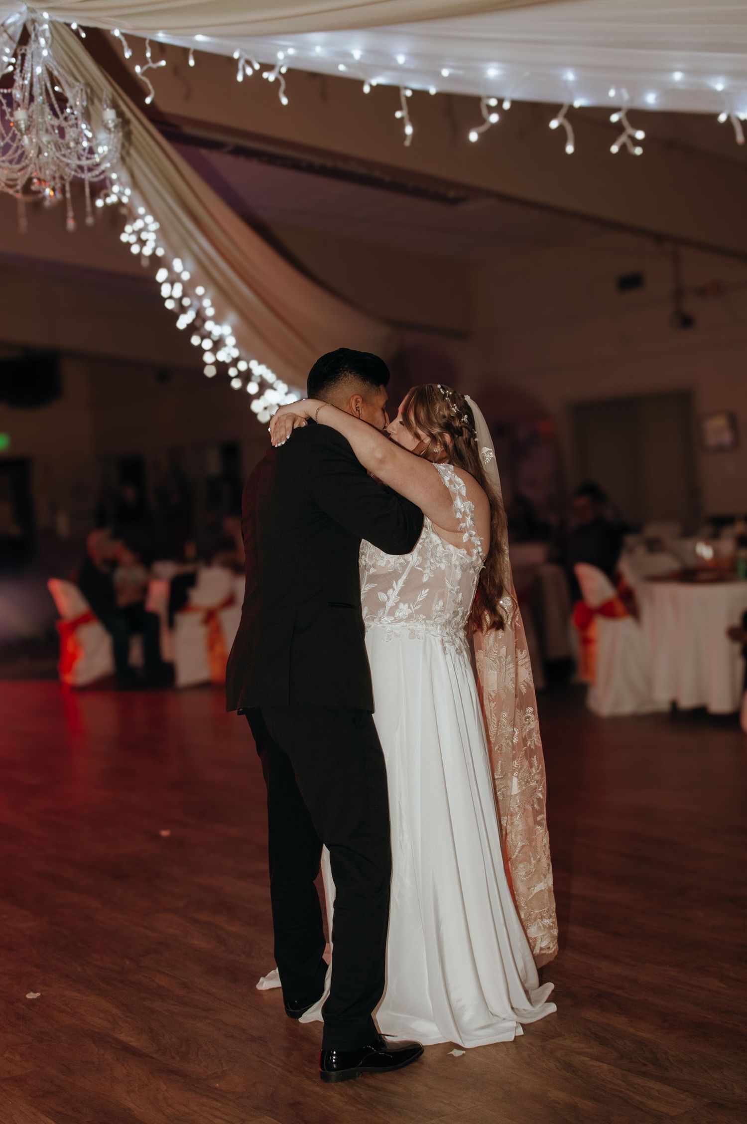 Wedding dance captured under twinkling lights in an elegantly decorated reception venue.