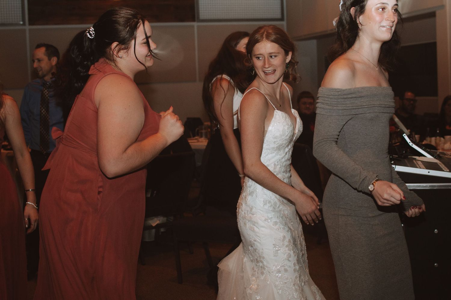 Wedding reception guests dance and mingle in a darkened indoor venue.