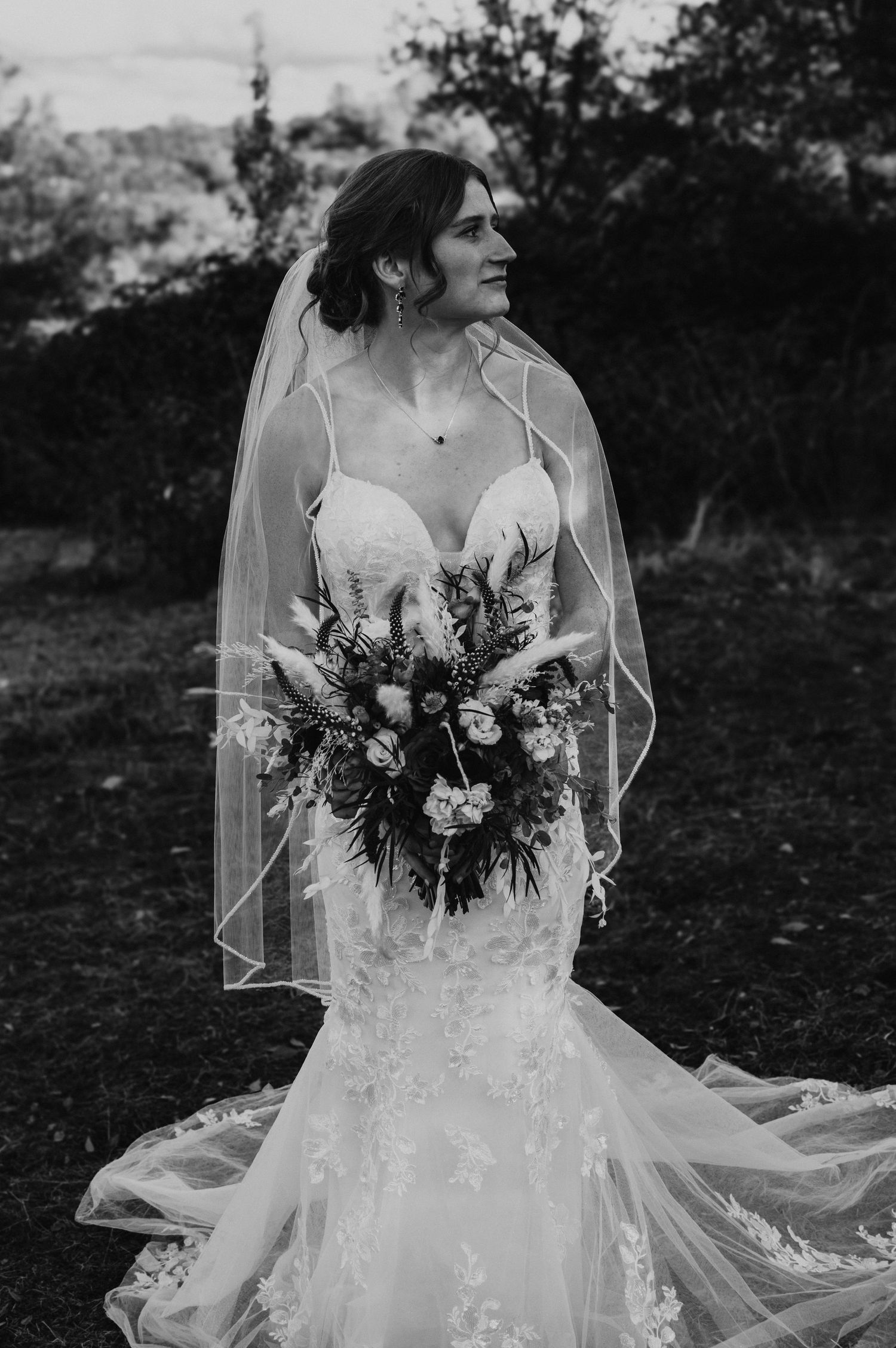 Elegant lace wedding dress with flowing veil captured in stunning black and white bridal portraits.