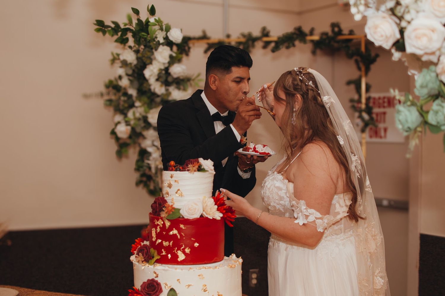 Couple shares a moment while feeding each other wedding cake at their reception.