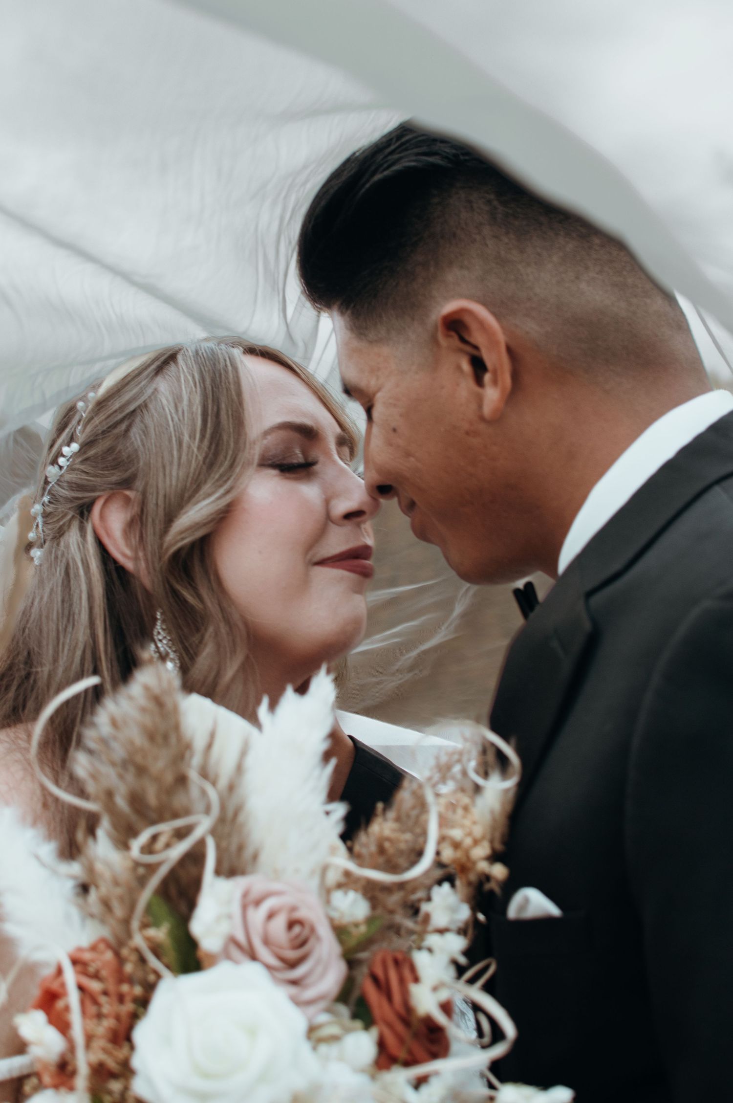 Close-up romantic shots of newlyweds with pink and white floral bouquet details.