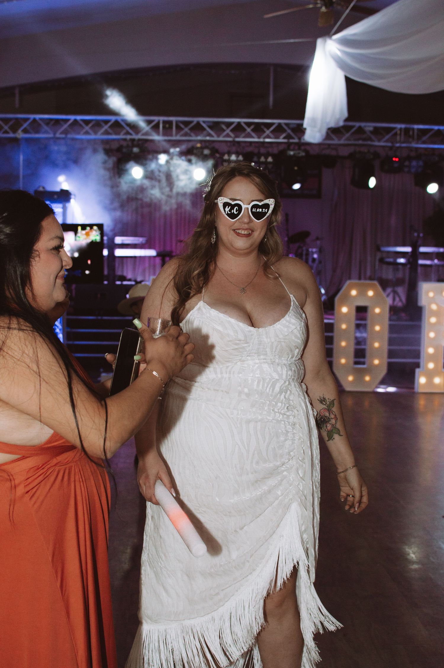 A festive reception scene with the bride dancing in a fringed dress and sunglasses.