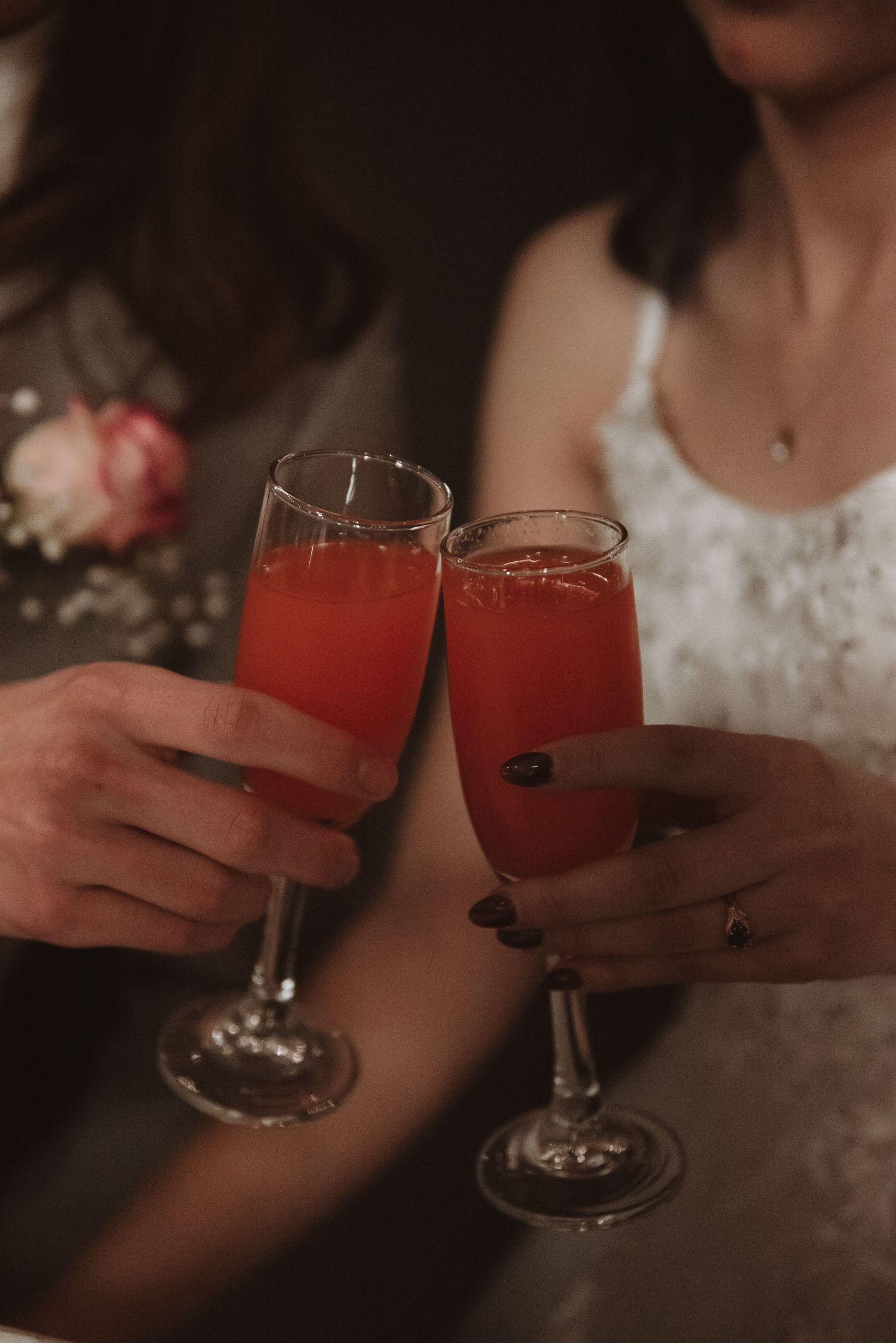Wedding guests clink glasses filled with red cocktails during the reception celebration.