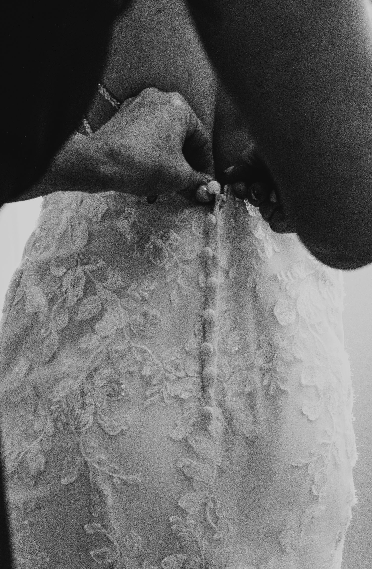 Detailed close-up shot of delicate lace appliques on white wedding dress bodice.