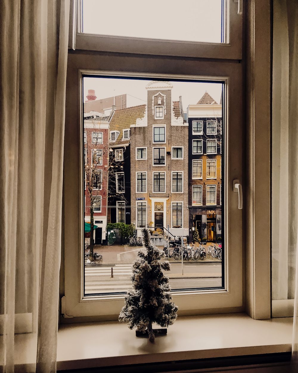 View through large windows showing traditional Dutch buildings and architecture on a city street.