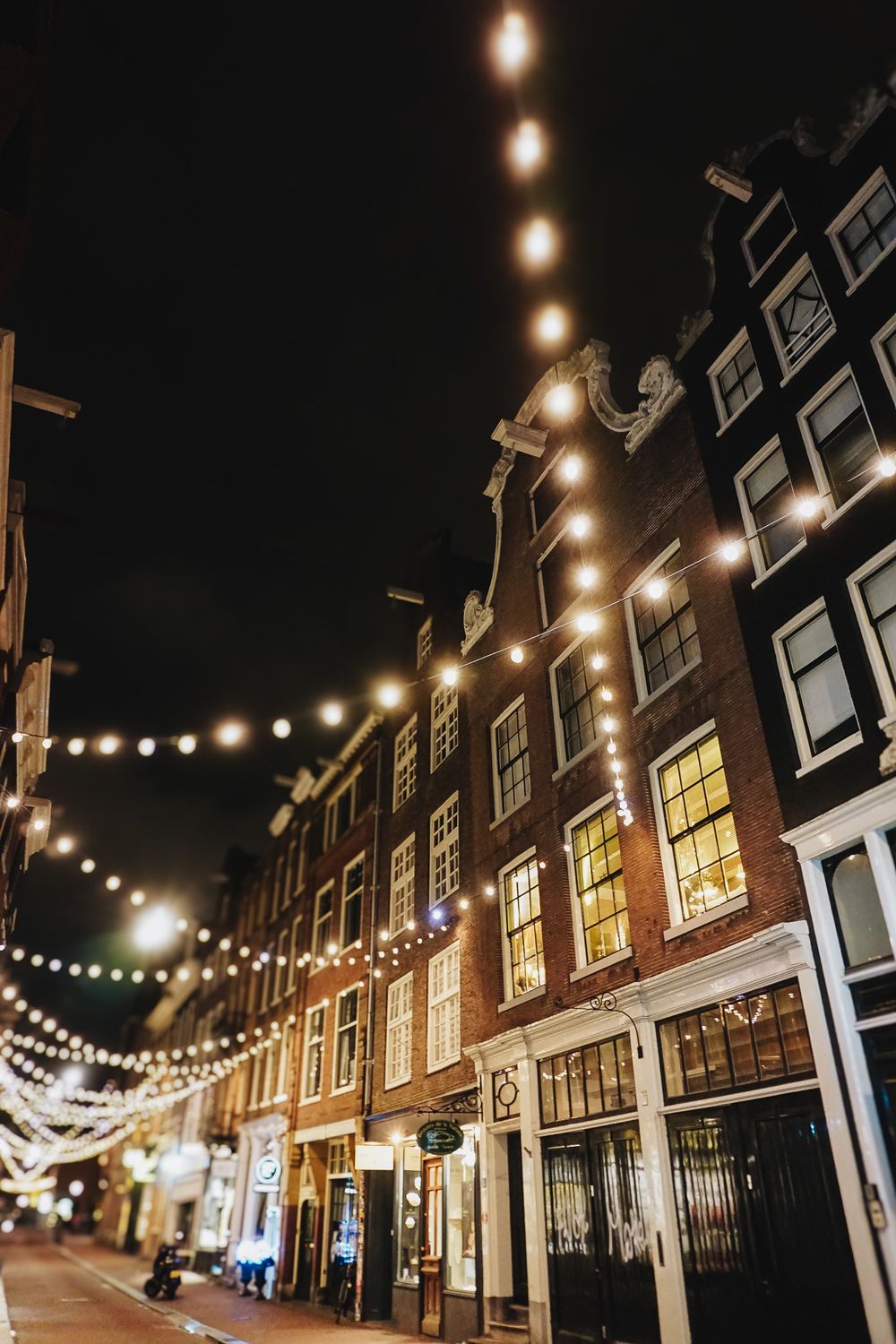 String lights illuminating historic Dutch row houses at night creating a magical atmosphere.