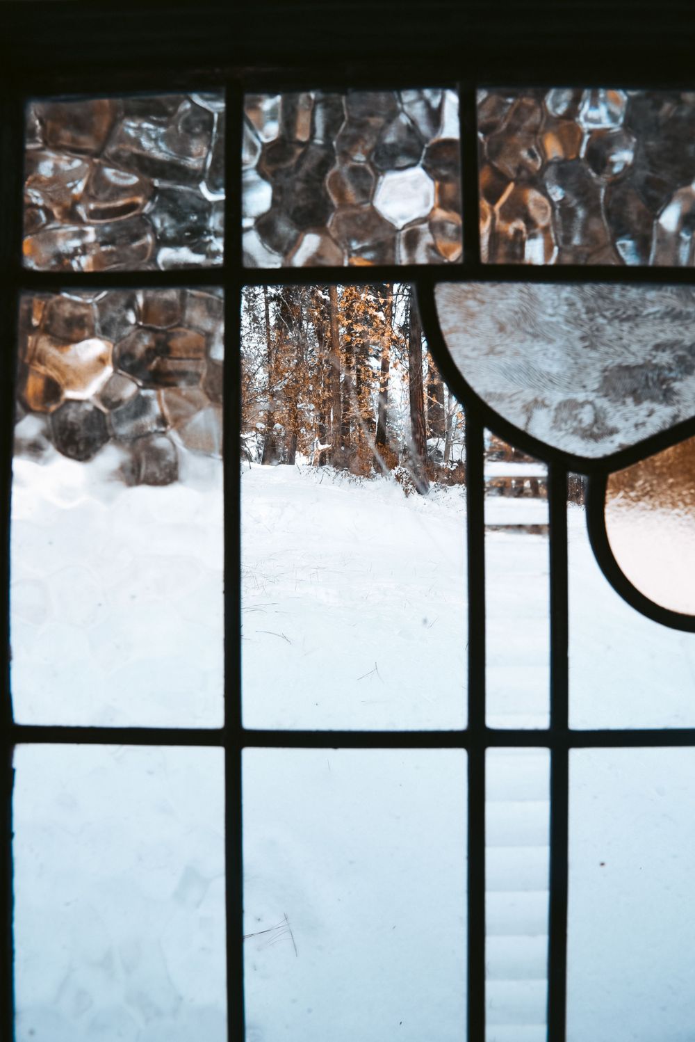 Snow-covered geometric window frame pattern with ice formations.