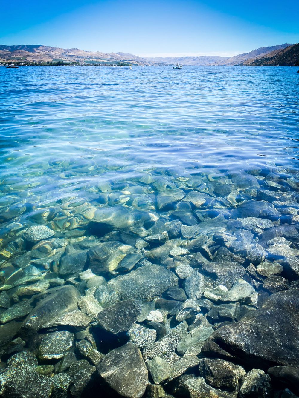 Crystal clear turquoise water reveals rocks beneath the surface of a mountain lake.