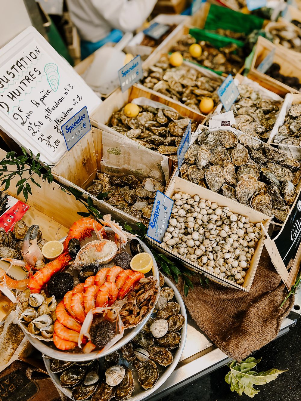 Fresh seafood display at market showing oysters, shrimp and shellfish on ice.