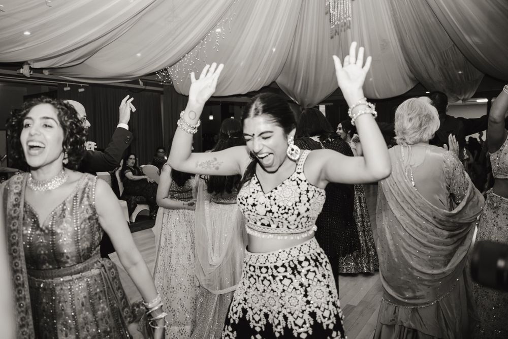 Black and white photo of guests dancing enthusiastically at a wedding celebration.