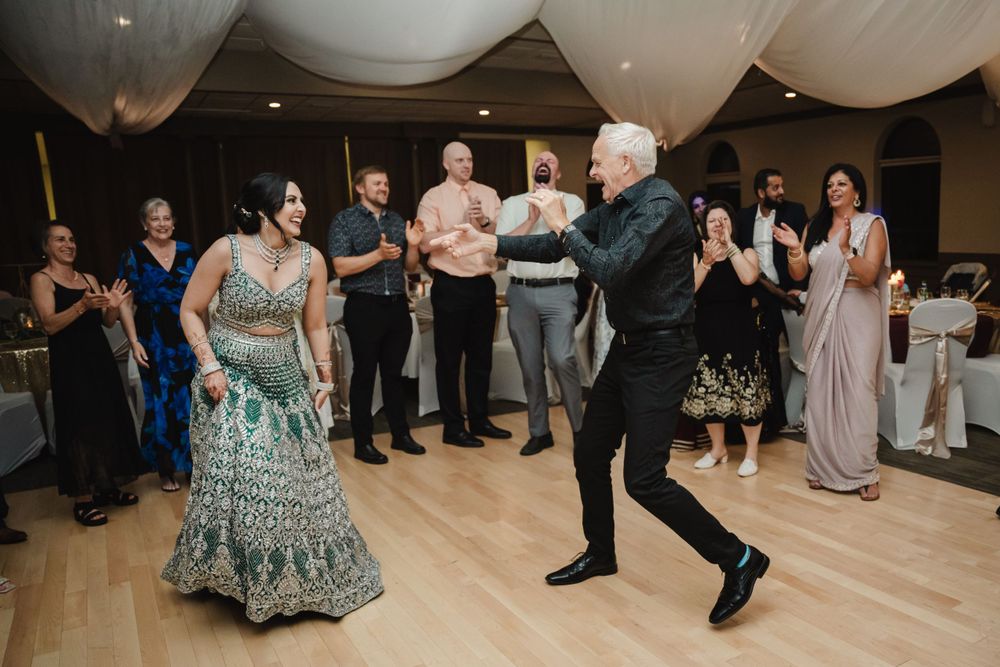 Wedding guests enjoy dancing and celebrating on the wooden dance floor under draped fabric ceiling.