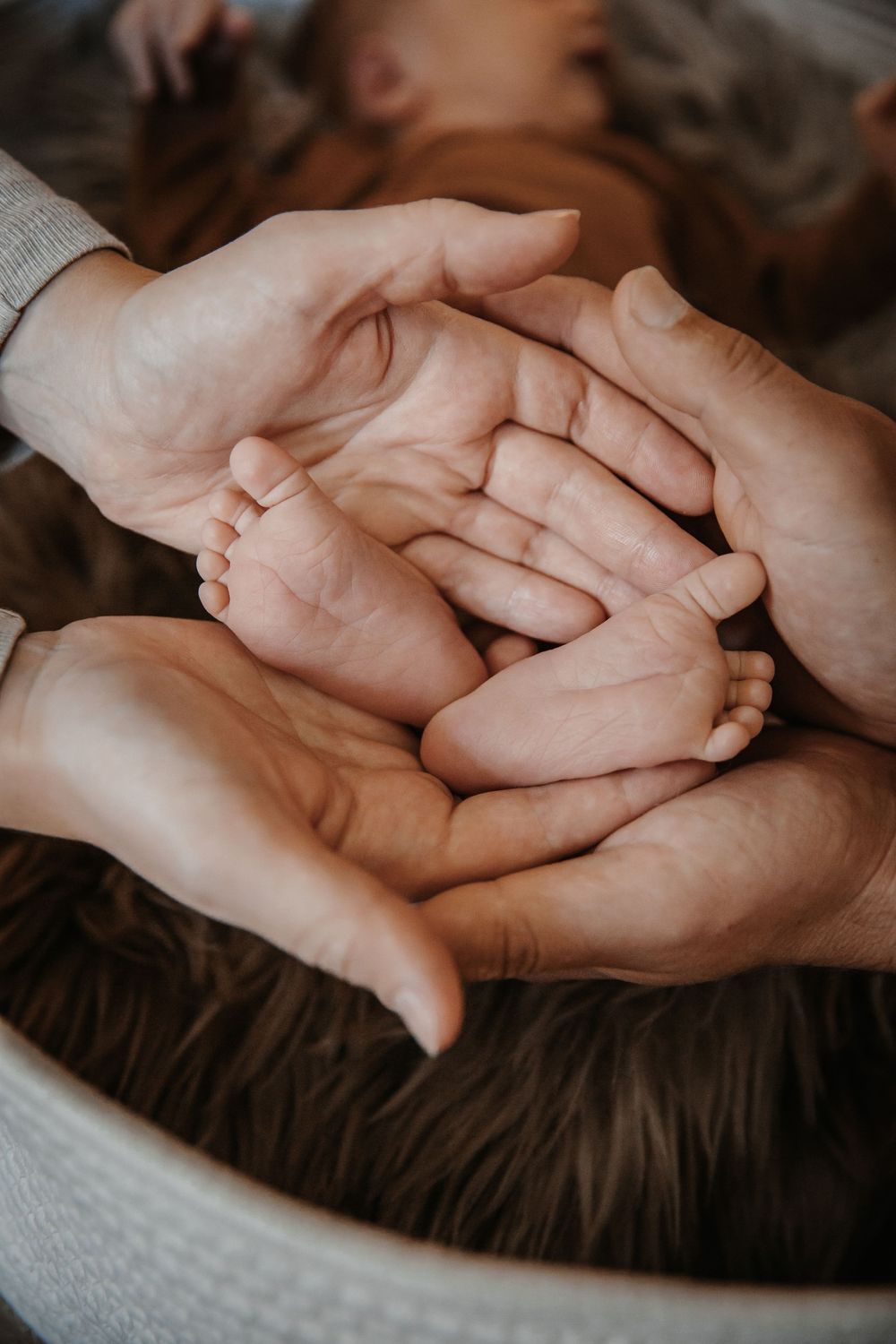 Close-up of hands tenderly holding each other against a dark background.