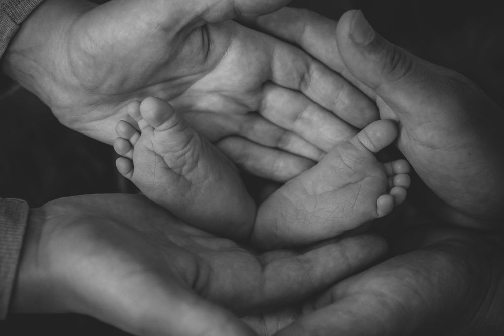 Intimate black and white photograph of hands gently touching and intertwining.