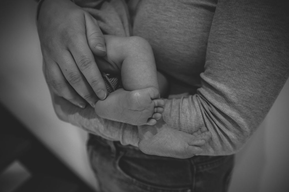 Artistic black and white photo of hands holding a baby.