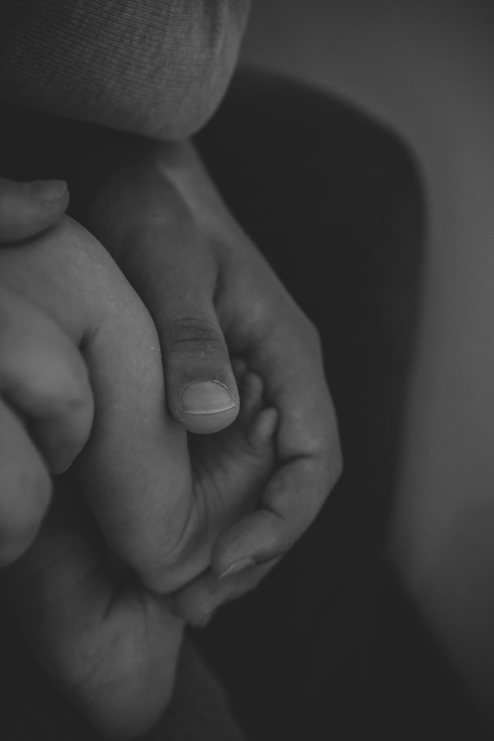 Moody black and white close-up of hands gently touching.