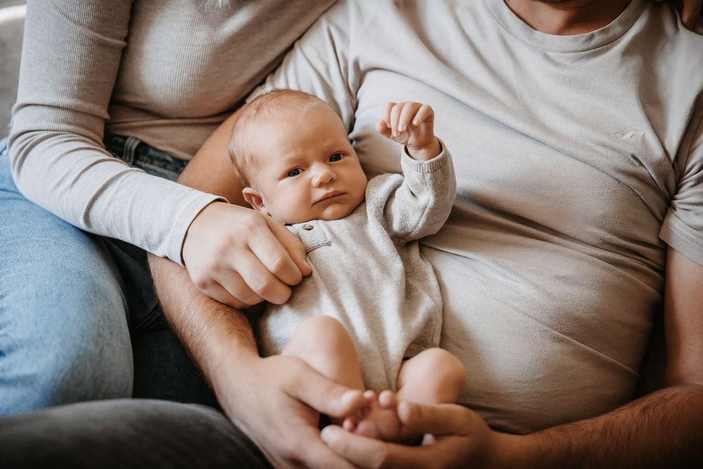 Intimate family portrait showing parents bonding with their newborn baby.