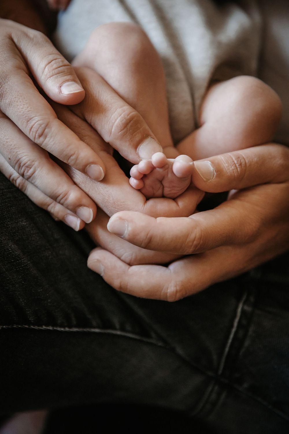 Close-up of hands gently cradling a small ultrasound photo in warm lighting.
