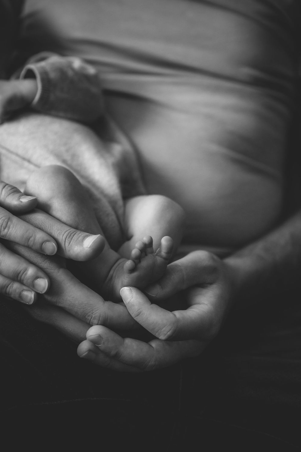 Black and white artistic shot of hands holding an ultrasound photograph.