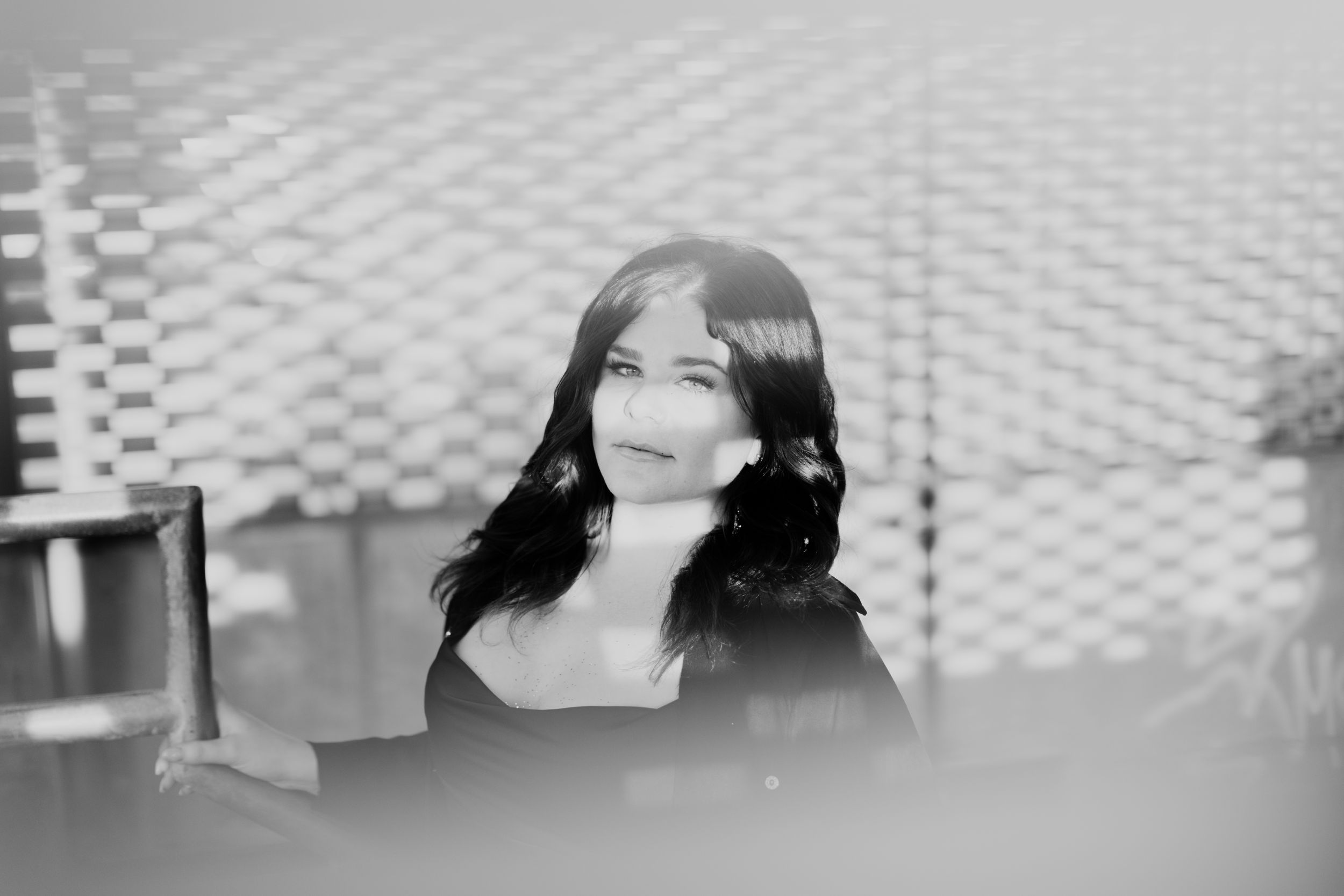 Black and white close-up portrait with geometric pattern background.