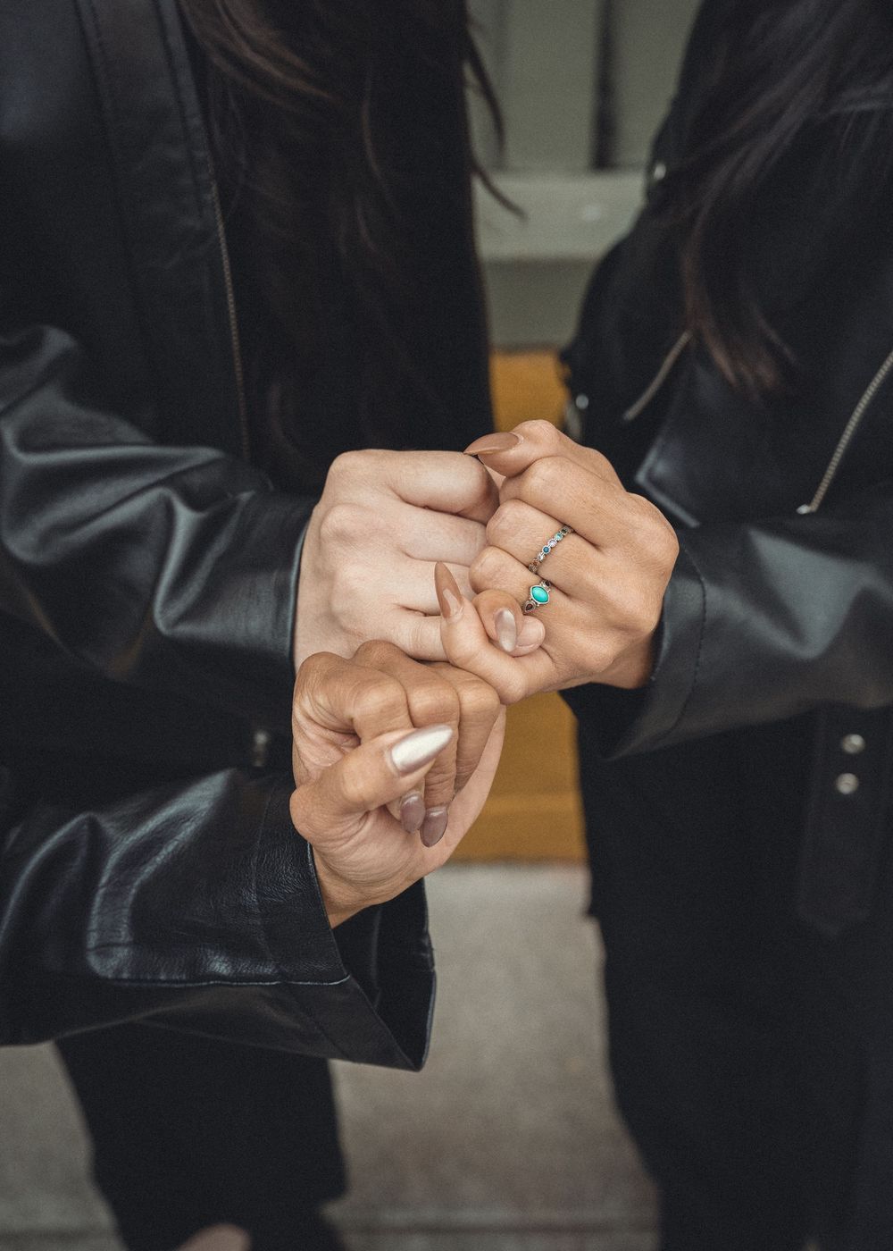 Several sequential images showing hands fidgeting with and adjusting rings on fingers while wearing a black jacket.