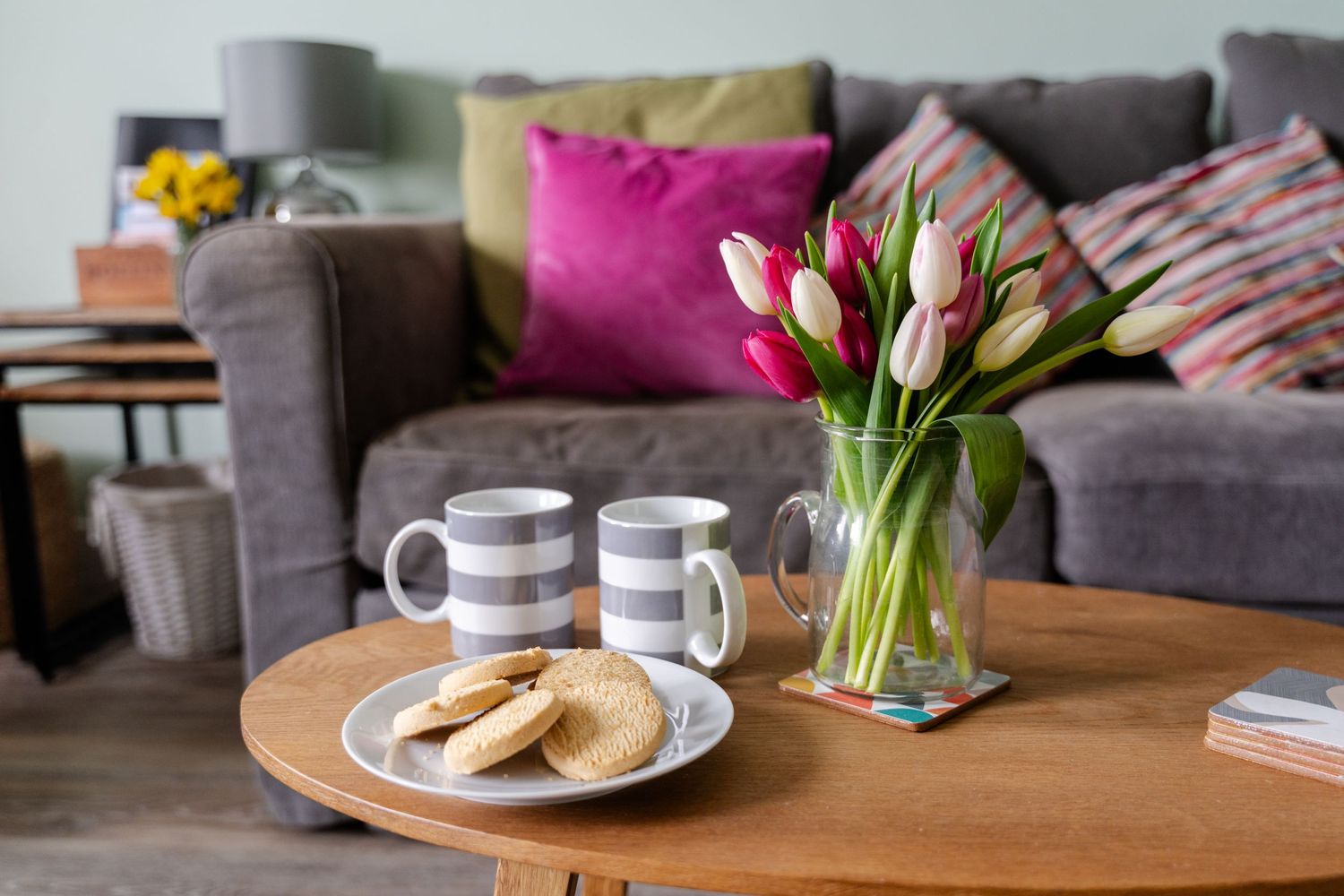 styled holiday let photography of living room sofa and coffee table styled with flowers and tea and biscuits