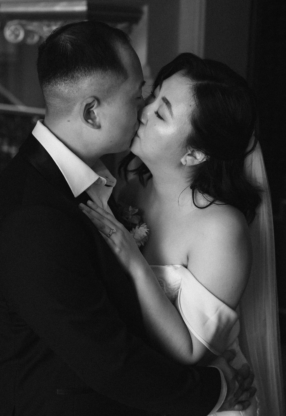 A romantic black and white photo series of a couple sharing intimate kisses in dramatic lighting.