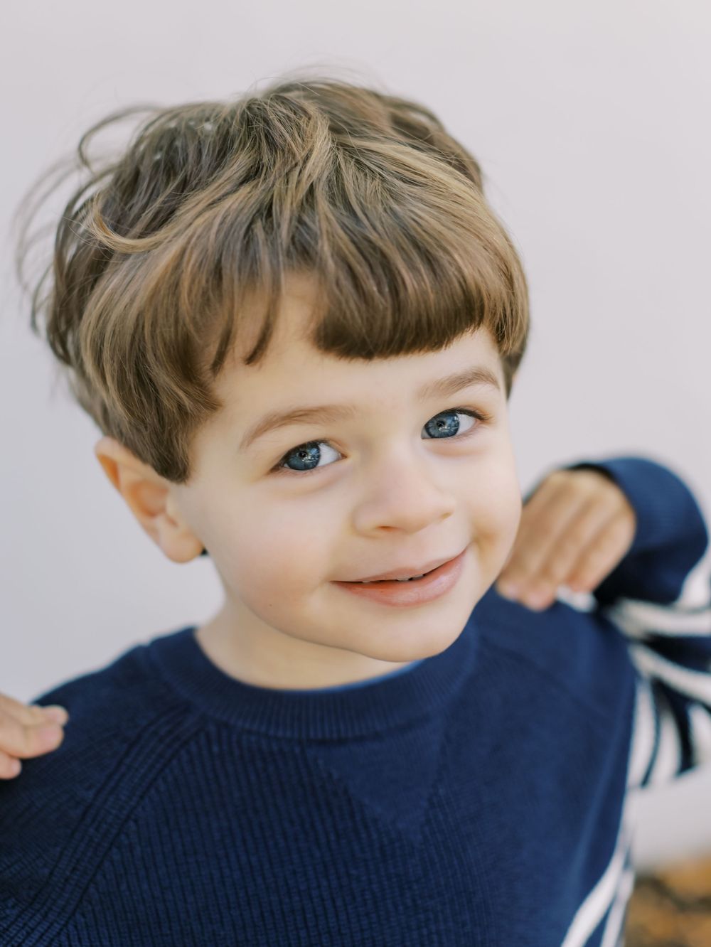 A sequence of five candid photos shows a child wearing a navy blue sweater making expressive smiling faces.