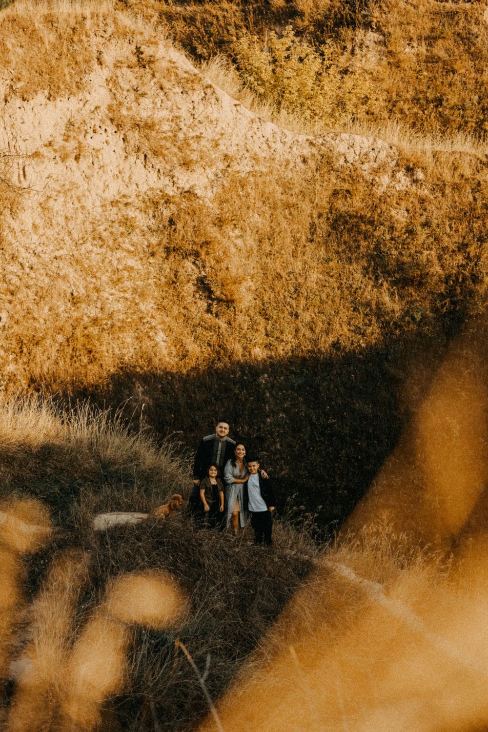 A distant silhouette of people standing together on a hillside at golden hour with warm autumn tones and shadows.