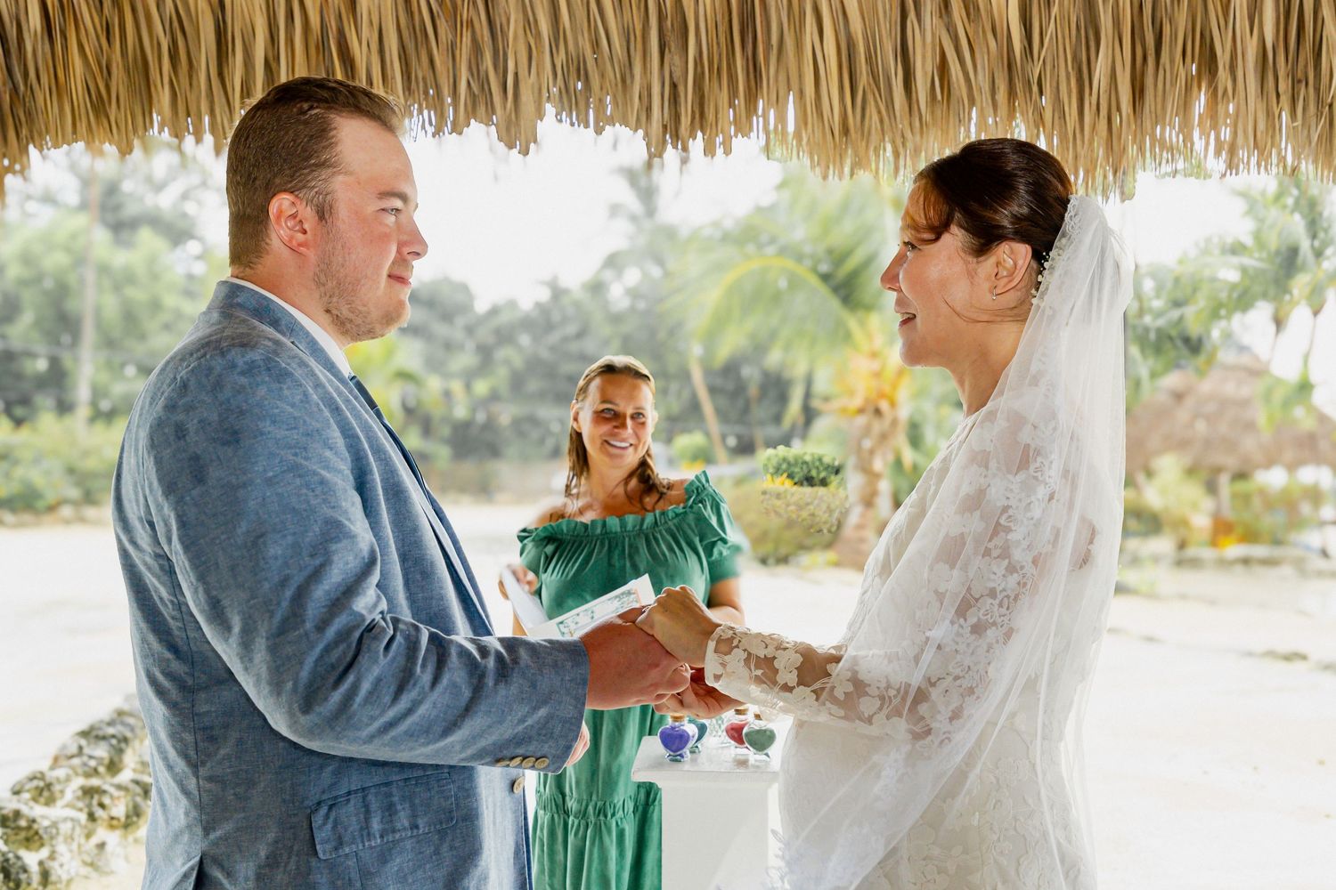 A couple shares a special moment under a thatched roof pavilion at a beach wedding.