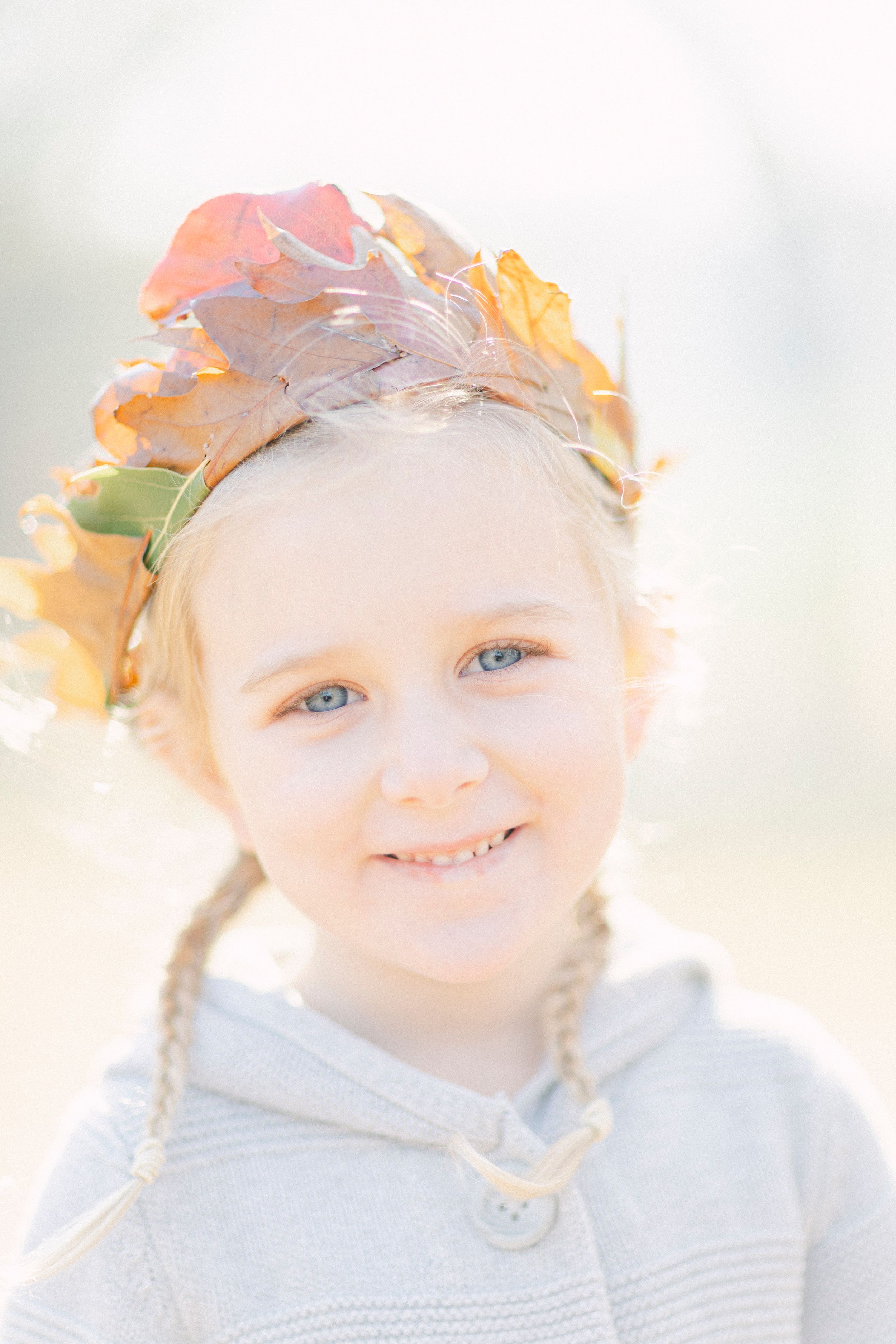 A delicate portrait with autumn leaves crown and soft natural lighting.