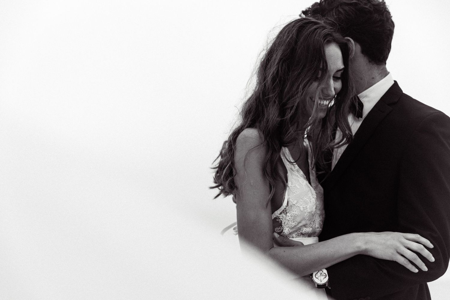 Intimate black and white portrait of couple embracing in formal wedding attire.