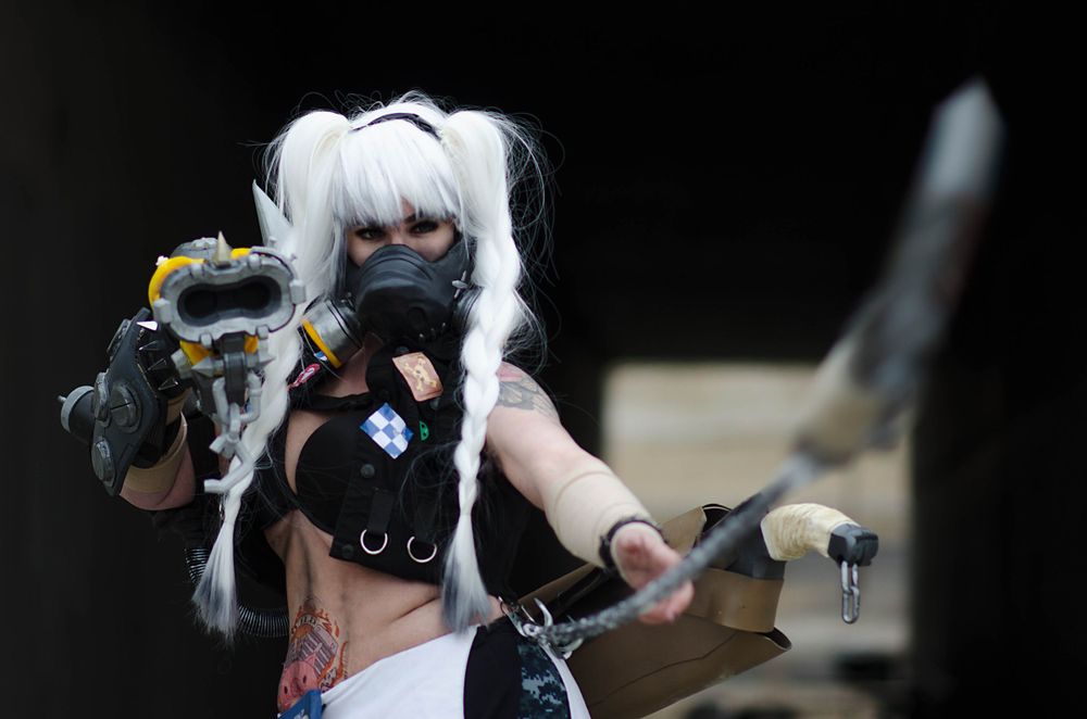 Black and white photo of post-apocalyptic cosplay with weapons and white pigtails.