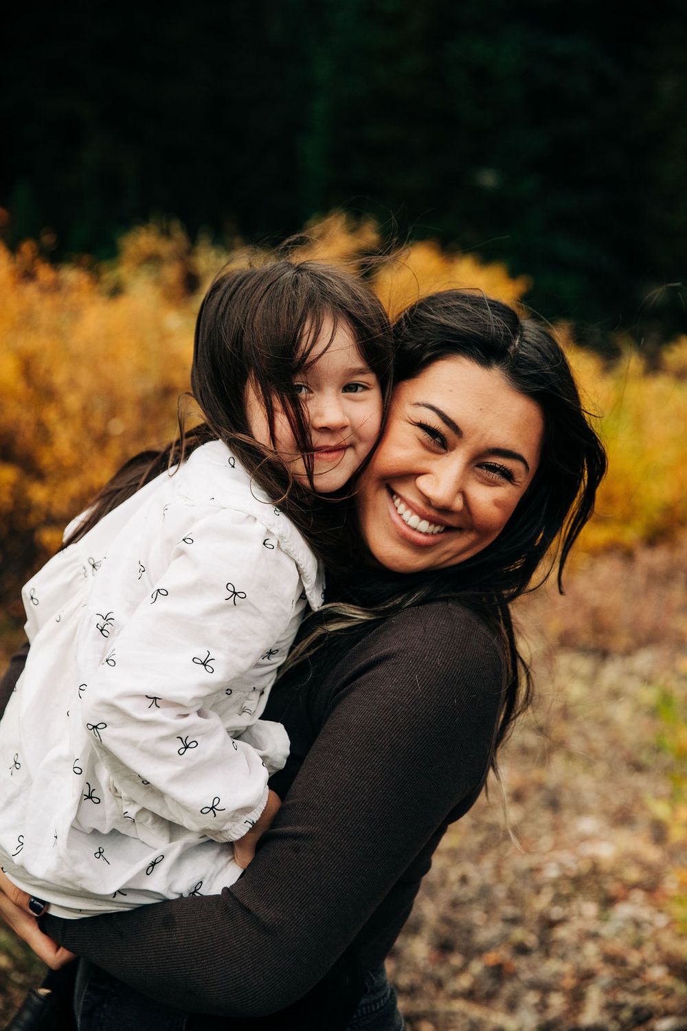 A heartwarming outdoor photoshoot showing playful embraces against a backdrop of autumn foliage.