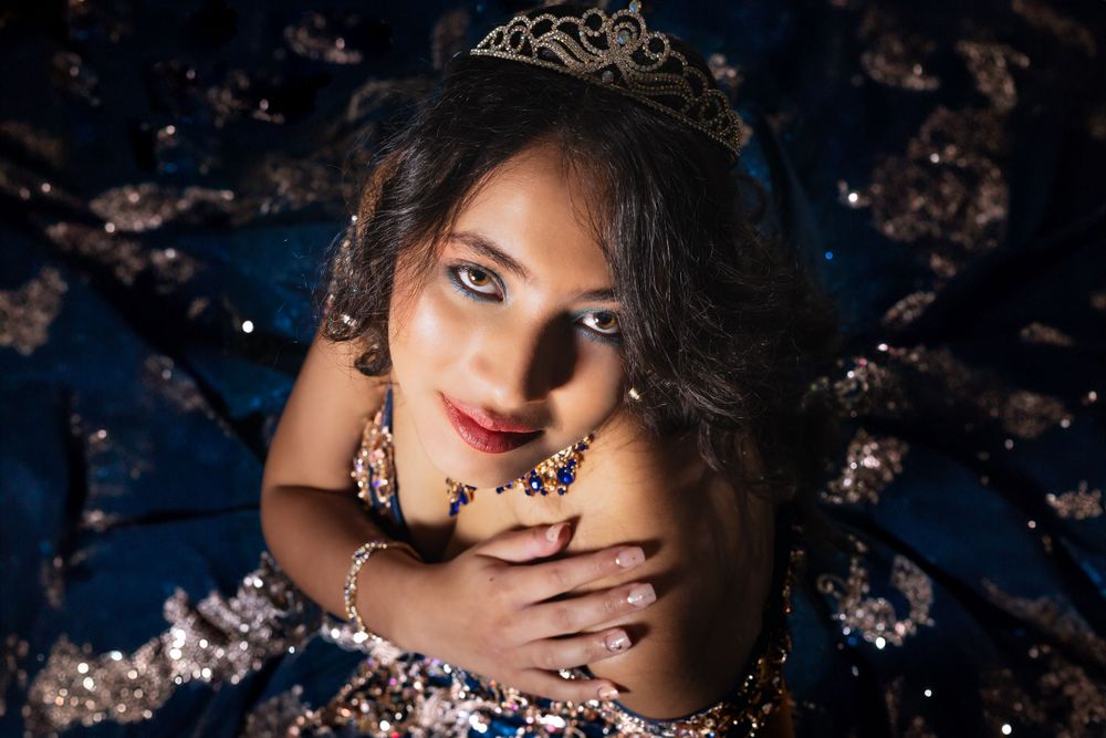 Dramatic portrait session featuring a navy blue gown with metallic details against a starlit background.