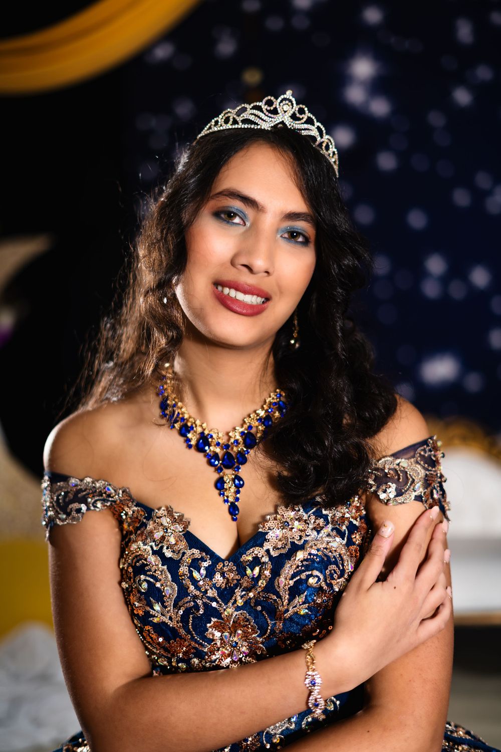 Regal quinceañera portrait featuring a tiara and navy blue gown with copper embellishments.